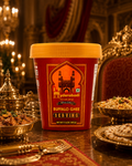 A tub of Hyderabadi Buffalo Ghee Serving, featuring a red label with gold detailing and a yellow lid, set on a decorated table with traditional Indian dishes and ornate gold-toned serving vessels.